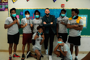 Kevin Love Smiling With High School Teens in Classroom